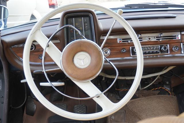 Cleaned Mercedes-Benz interior — white steering wheel, wood dashboard and instrument panel.