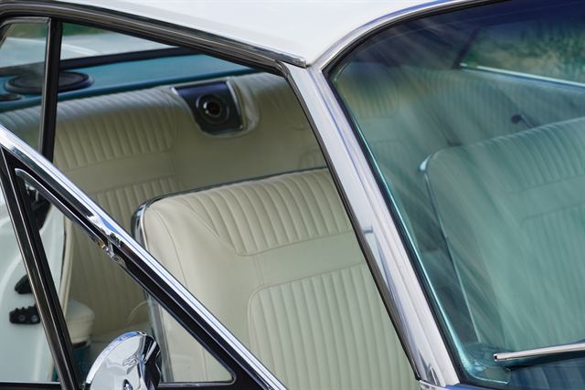 Cream vinyl seat and door trim of a Chevrolet Impala seen through the cleaned side glass.